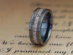 a wedding ring with wood inlays on top of a piece of parchment paper