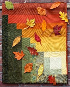 a quilted wall hanging with autumn leaves on it's sides and the colors of fall