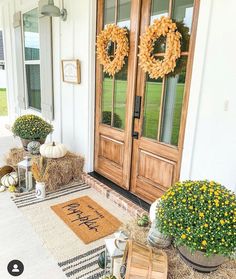 front porch decorated for fall with hay bales, pumpkins and wreaths on the door