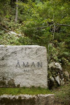 there is a large stone with the name aman on it in front of some trees