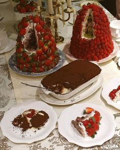 a table topped with cakes and desserts covered in chocolate cake frosting next to strawberries