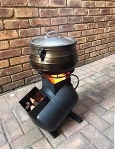 an outdoor bbq is sitting on the ground next to a brick wall