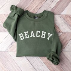 This Beachy Sweatshirt is the perfect gift for the beach lovers in your life! It features the trendy varsity style that will be loved for years to come!  This unisex, heavy blend crewneck sweatshirt is pure comfort and will quickly become your go-to. COLOR: This Gildan 18000 sweatshirt comes in several colors, look at the drop down for options.   SIZING: These sweatshirts are UNISEX in size.  Please check the size chart in listing photos for best fit!   MATERIAL:  -Made from polyester and cotton with a ribbed knit collar, it retains its shape even after washing. There are no itchy side seams on these sweaters and the tag is tear-away.  -Using a medium-heavy fabric blend of 50% cotton and 50% polyester, this sweatshirt feels cozy and is the perfect choice for those colder months. -100% ethi Trendy Letter Print Sweatshirt For Beach, Green Sporty Top For Beach Season, Sporty Green Tops For Beach Season, Sporty Green Beach Tops, Beach Season Sweatshirt With Letter Print, Letter Print Sweatshirt For Beach Vacation, Cotton Sweatshirt For Beach Vacation, Cotton Sweatshirt For Beach Season Vacation, Cotton Sweatshirt With Letter Print