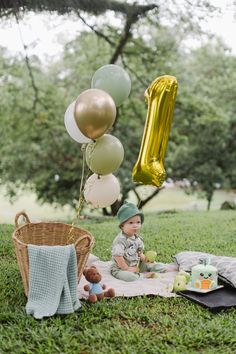 a baby sitting in the grass with balloons