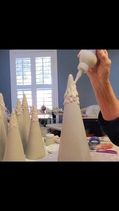 a person is pouring something into some white cone shaped cones on a table in front of windows