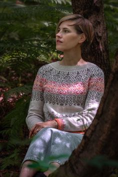 a woman sitting on the ground next to a tree