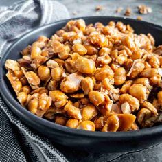 a black bowl filled with nuts on top of a gray cloth next to a napkin