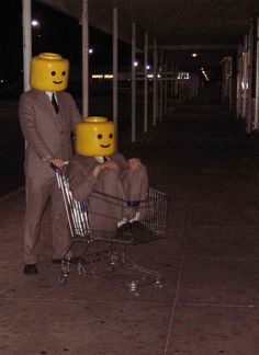 a man in a suit pushing a shopping cart with two legos on his head