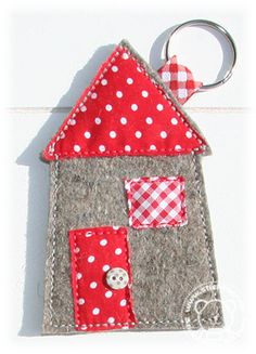 a house shaped keychain with a button on the front and a polka dot design on the back