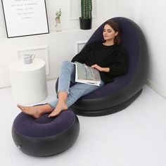 a woman sitting in a bean bag chair with a book on her lap and reading