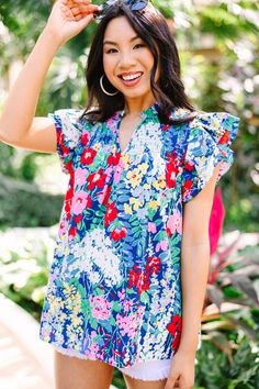 This colorful floral blouse is sure to make you stand out from the crowd! With its vibrant color palette and smocked detailing, this blouse is the perfect way to express your unique style and let your personality shine. This blouse features short sleeves, ruffle detailing, a split v-neck, and a vibrant floral print.  Material has no amount of stretch.Cindy is wearing the small. Multicolor Printed Tops With Ruffle Sleeves, Multicolor Stretch V-neck Blouse, Stretch Floral Print V-neck Blouse, Stretch V-neck Multicolor Blouse, Stretch Multicolor V-neck Blouse, Multicolor Floral Print Flutter Sleeve Tops, Multicolor Floral Print Top With Flutter Sleeves, Multicolor Floral Print Tops With Flutter Sleeves, Summer Flutter Sleeve Printed Blouse