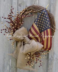 a wreath with an american flag and berries hanging on a wooden fence next to a burlock