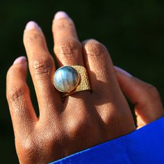 Like a jewel in our solar system, the ‘Earth’ ring stands out like no other with the beauty that only natural labradorite gemstone can bring. This attractive and comfortable ring with its appealing gold texture is one you’ll want to wear as often as possible on its own or stacked with other jewels.   Each ring will arrive in a Yaa Yaa London jewellery box with a pouch and polishing cloth. Colour intensities vary. These are semi-precious stones.  Gold and Rose Gold plating can wear off so we do n Gold Rings With Labradorite Natural Stones, Adjustable Labradorite Open Ring, Yellow Gold Labradorite Round Jewelry, Elegant Adjustable Labradorite Ring, Nature-inspired Round Labradorite Jewelry, Artisan Labradorite Ring Jewelry, Artisan Labradorite Jewelry For Anniversary, Earth Ring, Adjustable Gold Ring