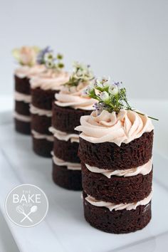 three chocolate cakes with white frosting and flowers on each one slice are sitting on a plate