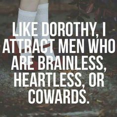 a person standing in the grass with their legs crossed and texting like dorothy, i attract men who are brainless, heartless, or co