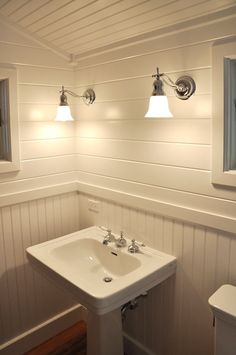 a white sink sitting under two lights in a bathroom