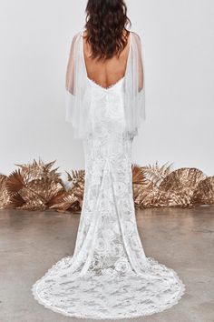 the back of a woman wearing a white wedding dress with sheer sleeves and an open shoulder