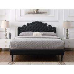 a bed with a black headboard and foot board in a white room next to two lamps