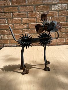 a metal sculpture on top of a wooden table next to a brick wall and floor