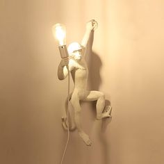 a lamp that is on the wall with a human figure holding a lightbulb