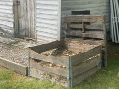 two wooden crates filled with dirt next to a building and grass covered yard in front of it