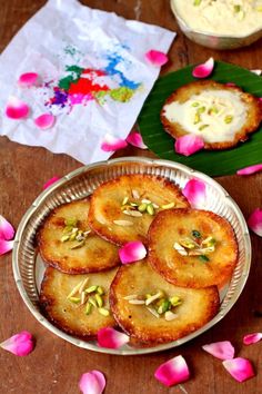 some food is sitting on a table with pink flowers and petals scattered around the plate