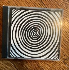 a cd case sitting on top of a wooden floor with a spiral design in the middle