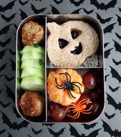 a bento box filled with fruit, cookies and other food items on a black and white tablecloth