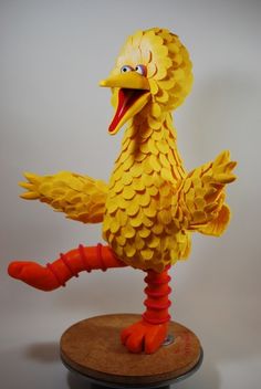 a yellow bird statue sitting on top of a wooden stand