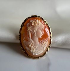 Incredible hand carved oval shell cameo, vibrant orange colour with white figure of a lady holding a rose.  Pre-loved item, some scratches on the back of the shell Size (approx.): 3.5cm tall, 2.5cm wide Stamped 585 14KT Gold Weight: 4.780g **FREE shipping within Canada and USA** If you have any questions or concerns, please do not hesitate to contact us. We will be more than happy to help you and answer any inquiries.  We invite you to check out our shop for more fabulous items! White Oval Cameo Brooches, Carved Oval Brooch As Gift, Carved Oval Brooch For Gift, Carved Oval Brooches As Gift, Collectible Oval Cameo Brooch, Oval Cameo Brooch For Anniversary, Collectible Oval Cameo Brooches, Oval Cameo Brooches As Gift, Vintage Orange Brooches For Wedding