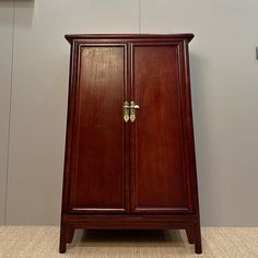 a wooden cabinet sitting on top of a carpeted floor next to a white wall