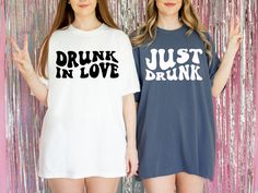 two women standing next to each other wearing t - shirts that say drink in love