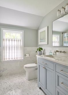 a bathroom with gray cabinets and white fixtures