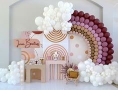 a room filled with balloons and decorations on the wall next to a white table topped with a cake