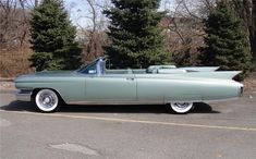 an old green car parked in a parking lot