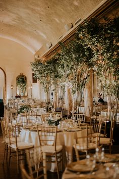 tables and chairs are set up for a wedding reception in an elegant setting with greenery