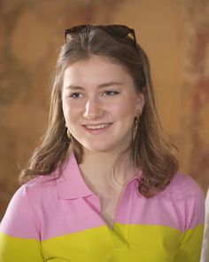 a young woman with sunglasses on her head smiling at the camera while wearing a pink and yellow shirt