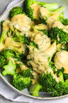 a bowl filled with broccoli covered in gravy on top of a table