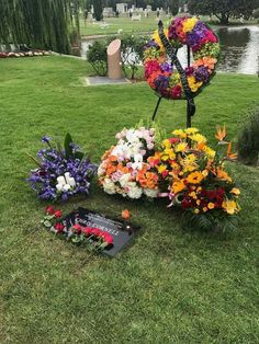 flowers are laid out on the grass in front of a pond and memorial wreaths