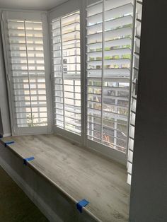 an empty room with white shutters on the windows and blue tape around the window sill