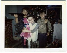 two boys and a girl standing in front of a christmas tree