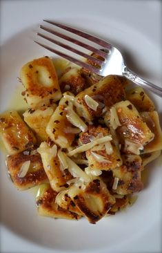 a white plate topped with pasta covered in cheese and sauce next to a silver fork