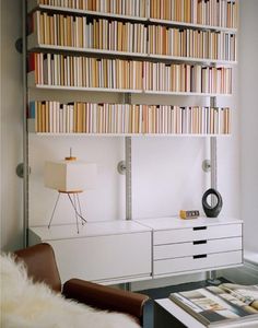 a living room filled with furniture and bookshelves next to a wall mounted book shelf