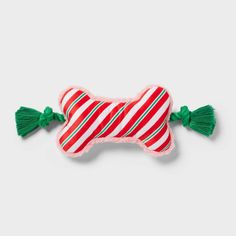 a red and white striped dog bone with green tassels on the side,