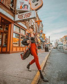 a woman is walking down the street in front of a guitar sign and storefront