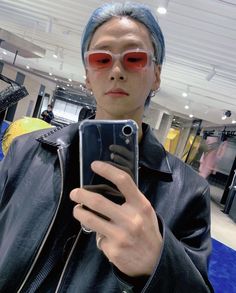 a man with blue hair and red sunglasses taking a selfie