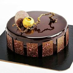 a chocolate cake with gold decorations on top is sitting on a black platter,