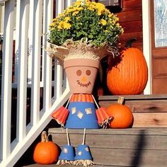 a scarecrow planter sitting on the steps with pumpkins and flowers in it