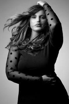 a woman with long hair and polka dot sleeves posing for a black and white photo