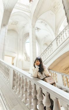 a woman sitting on top of a stair case next to a banister in a building